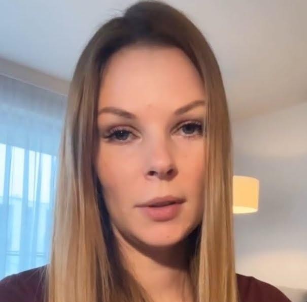 Małgorzata Tomaszewska prezentująca program w studiu telewizyjnym, trzymająca mikrofon, z dynamicznym tłem.