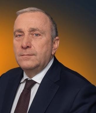 Grzegorz Schetyna podczas ożywionej dyskusji politycznej, uchwycony w momencie aktywnego uczestnictwa w spotkaniu lub debacie, otoczony innymi politykami.