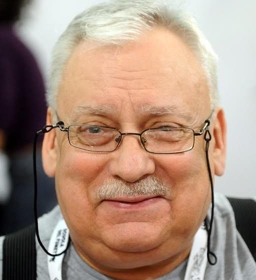 Stylizowany herb Łodzia, przedstawiający łódź na niebieskim tle, z elementami nawiązującymi do dawnych ziem polskich lub litewskich.