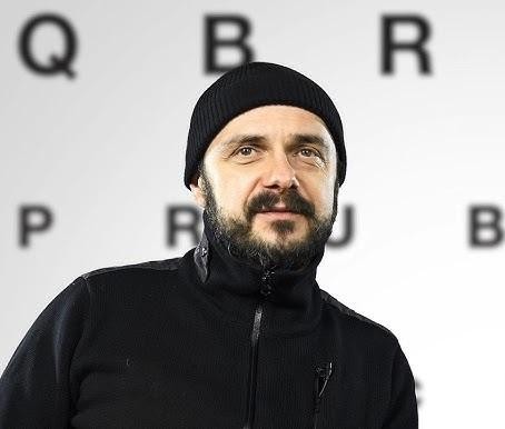 Arkadiusz Jakubik jako wokalista zespołu Dr Misio podczas energetycznego występu na scenie, otoczony instrumentami.