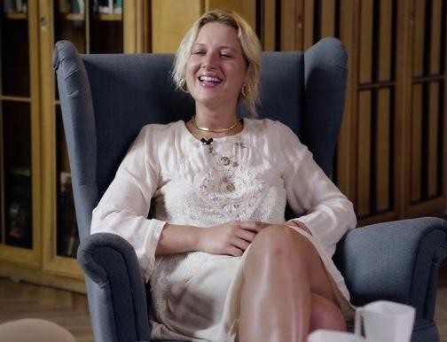 Aleksandra Domańska na planie filmowym, uchwycona w dynamicznej pozie, uśmiechnięta, z widoczną pasją do aktorstwa.