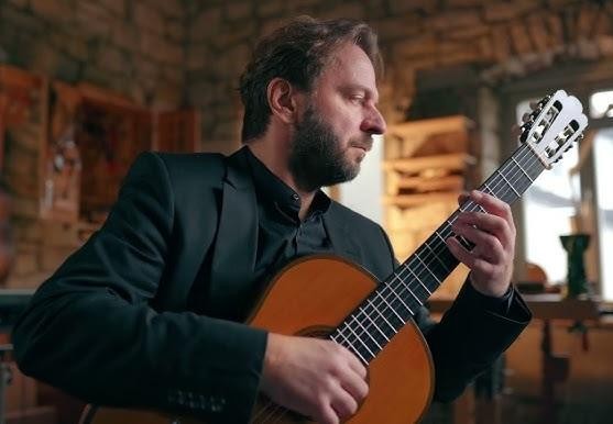 Zbliżenie na dłonie Marcina Dylli grające na gitarze klasycznej, ukazujące precyzyjne ruchy na gryfie i strunach.
