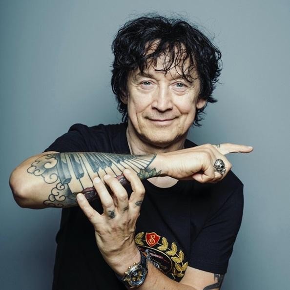 Jan Borysewicz w młodości, grający na gitarze z zespołem Lady Pank, czarno-białe zdjęcie oddające rockową energię lat 80.