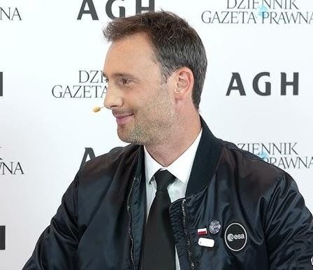 Portret Sławosza Uznańskiego, polskiego inżyniera i astronauty, z delikatnym tłem nawiązującym do kosmosu i technologii.